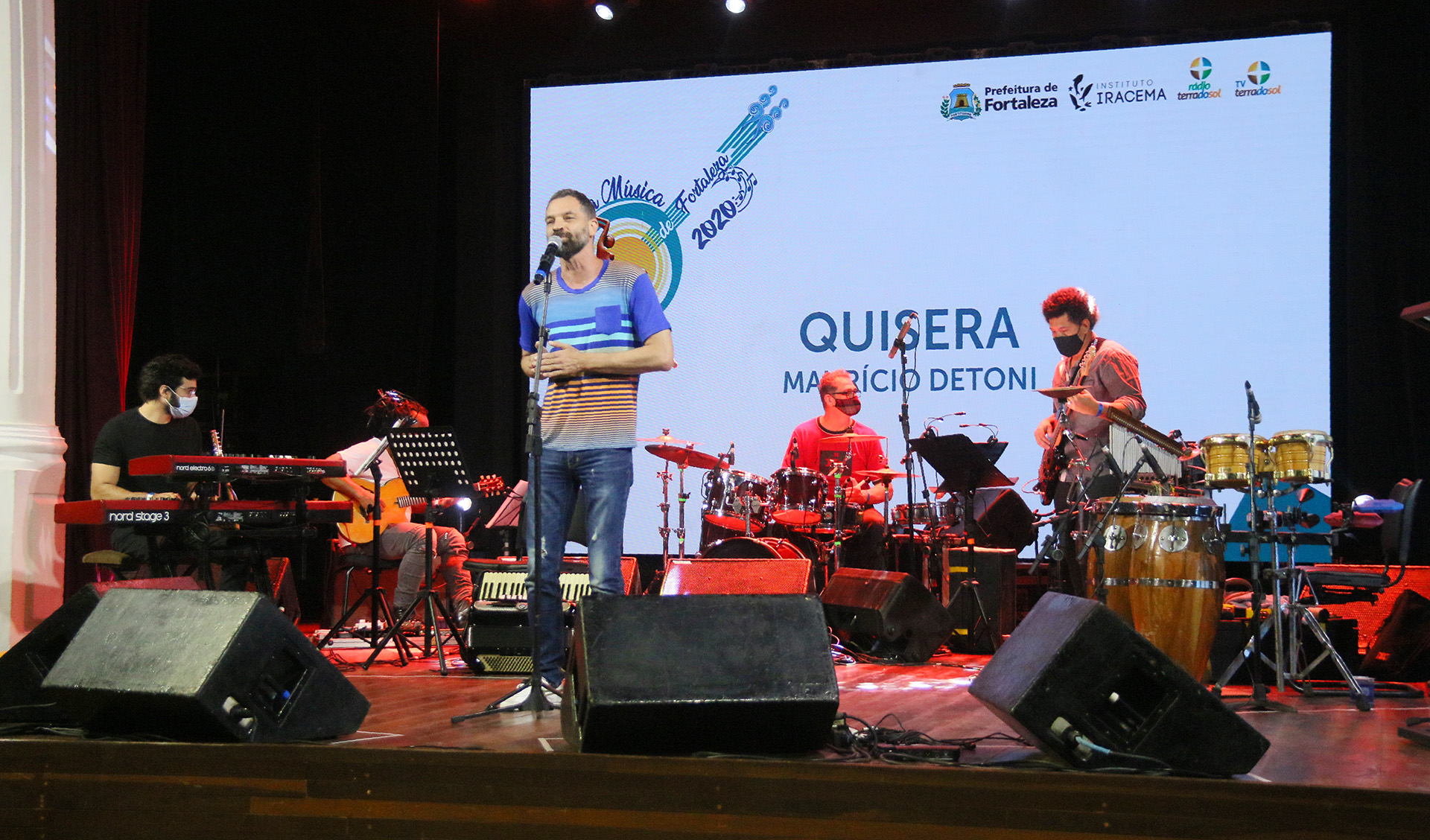 Mauricio Detoni cantando em palco com banda ao fundo